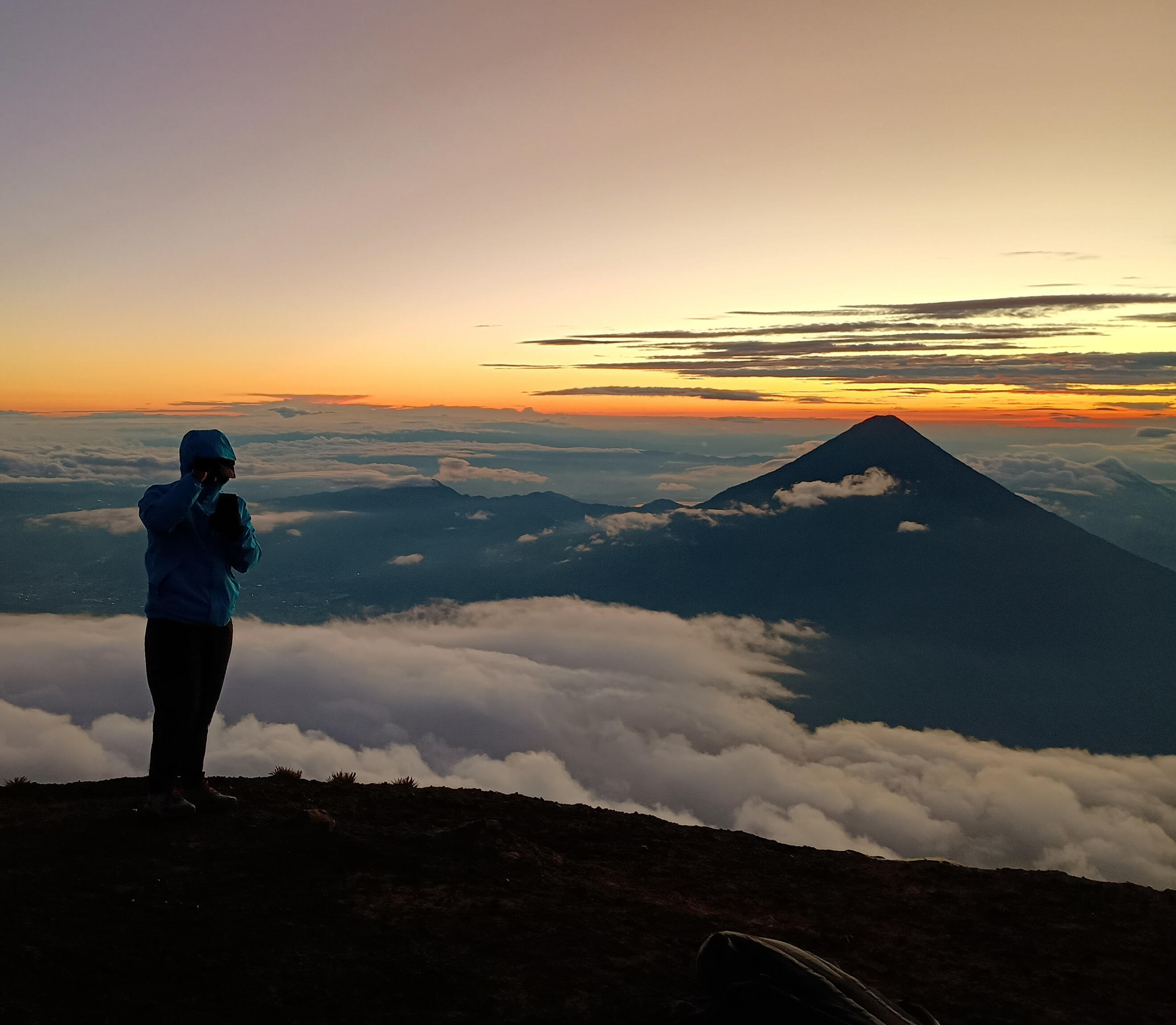 Photo of a woman sitting by a like overlooked by mountains